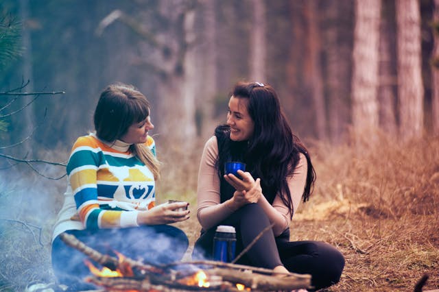 Two women chatting around a campfire