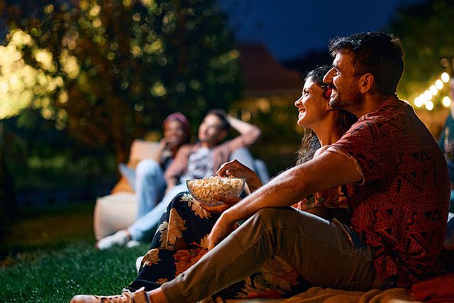 A group of people eating popcorn at an outdoor movie night