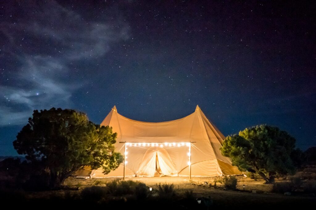 An illuminated tent under a starry sky