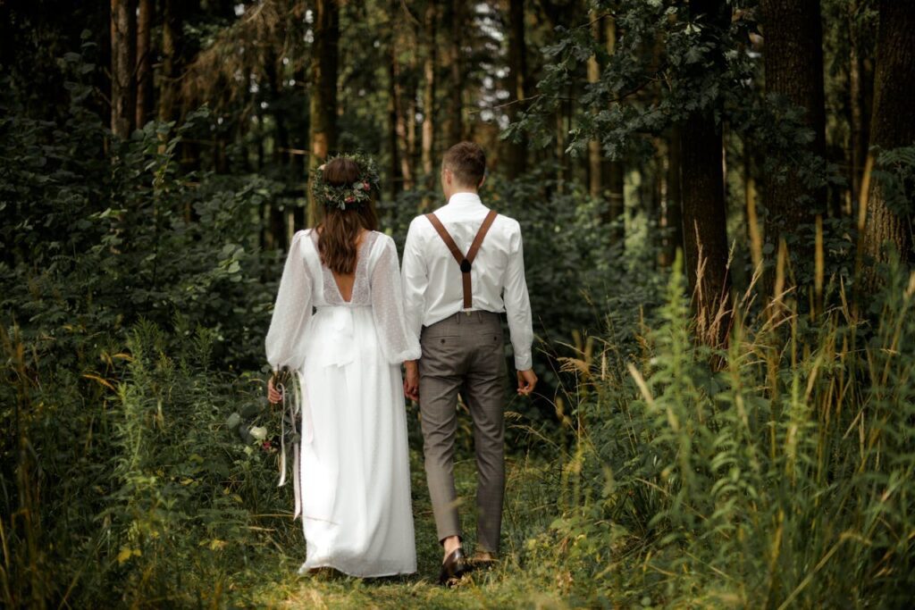 A bride and groom walking through a forest